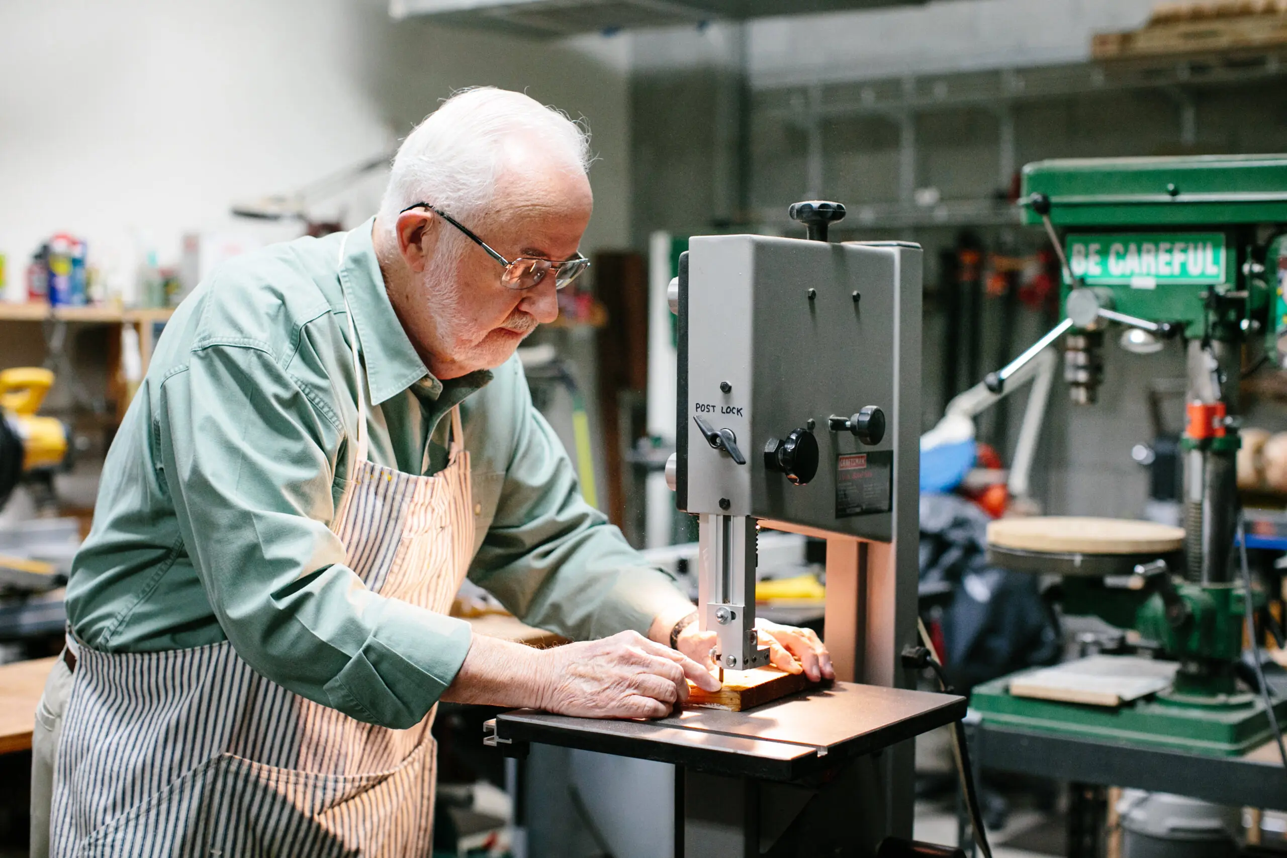 An older man makes a precise cut with a woodworking machine