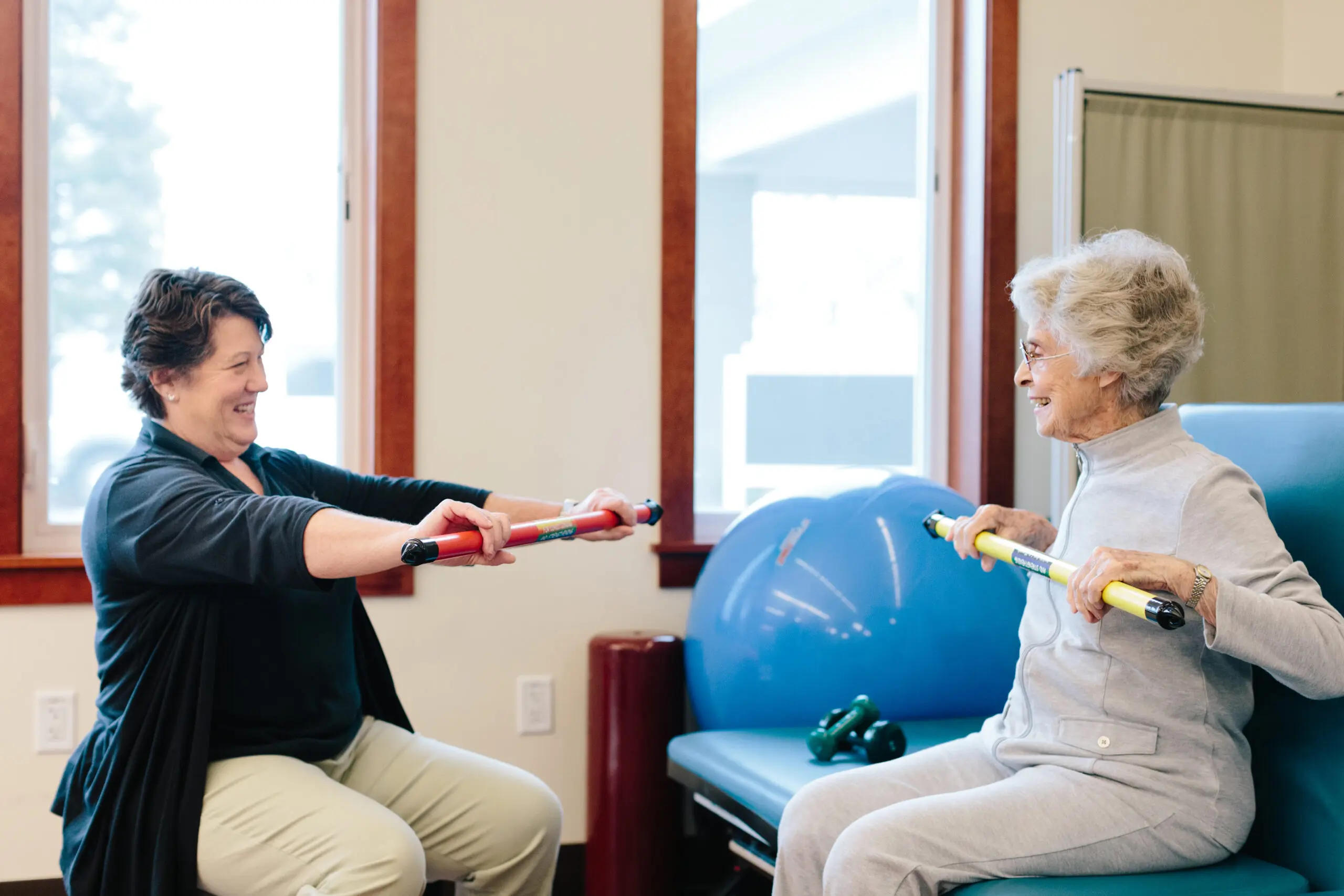 A physical therapist demonstrates an exercise for an older woman